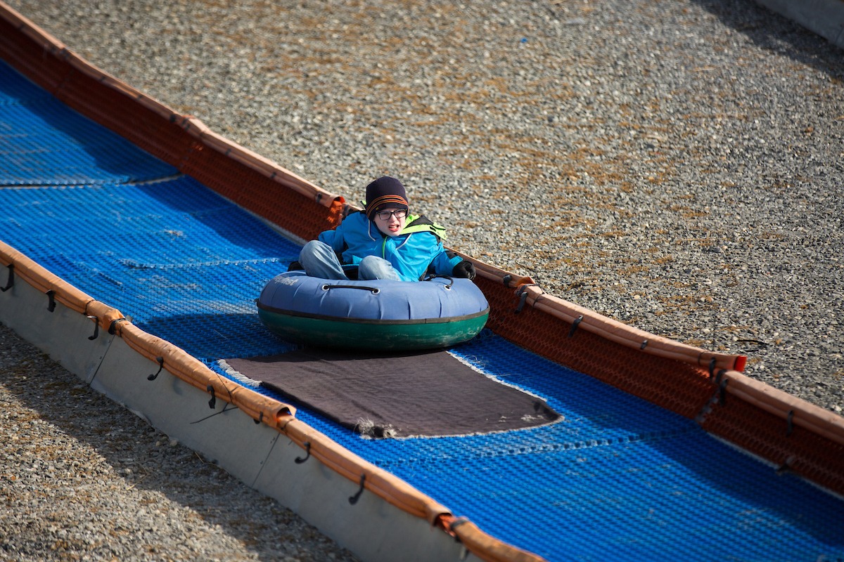 Young boy tubing down the slope at Snowflex during the LUOA Christmas Party