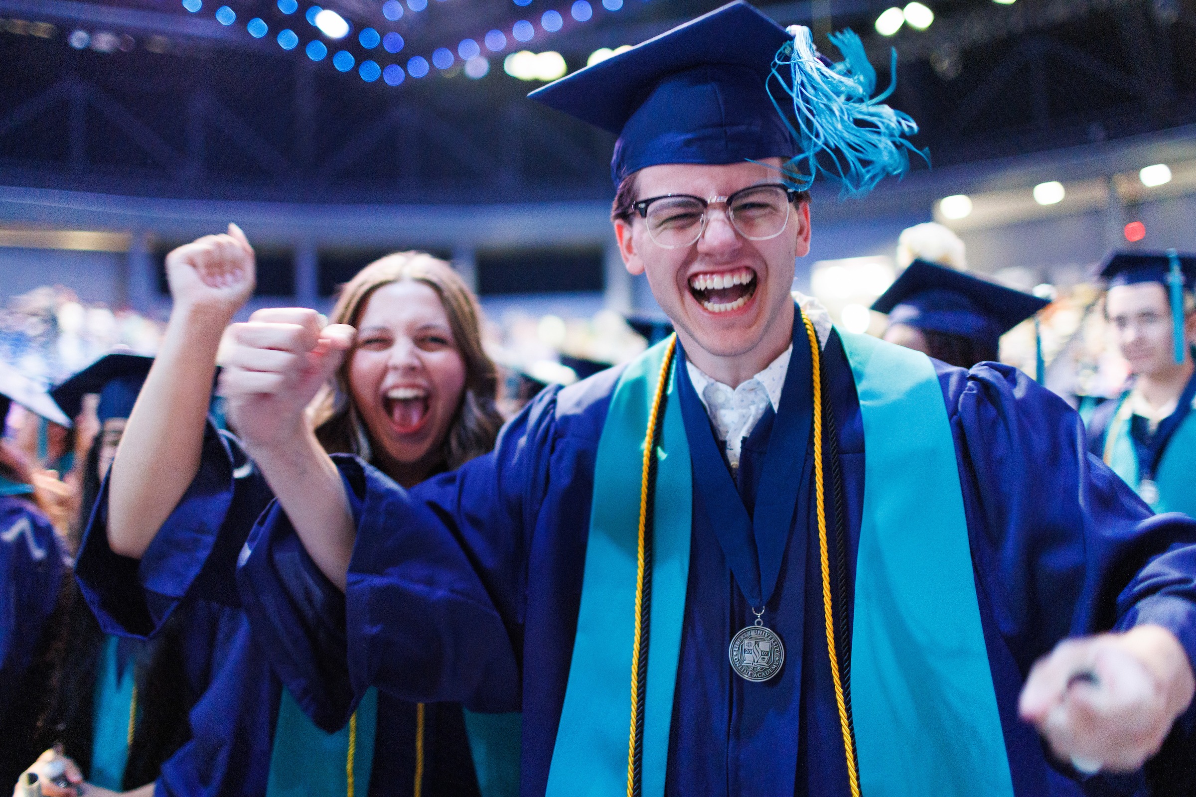 Male LUOA graduate smiling at the camera and pumping his fist