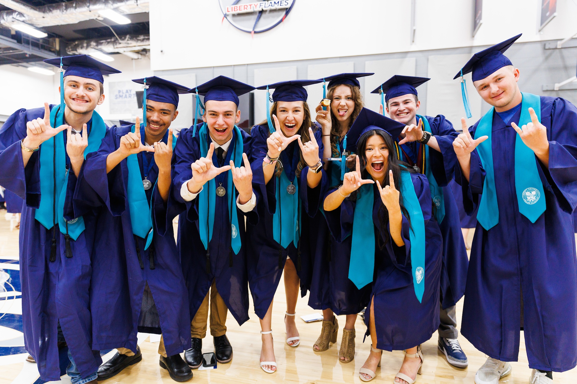 Group of LUOA graduates smiling and signaling LU with their hands