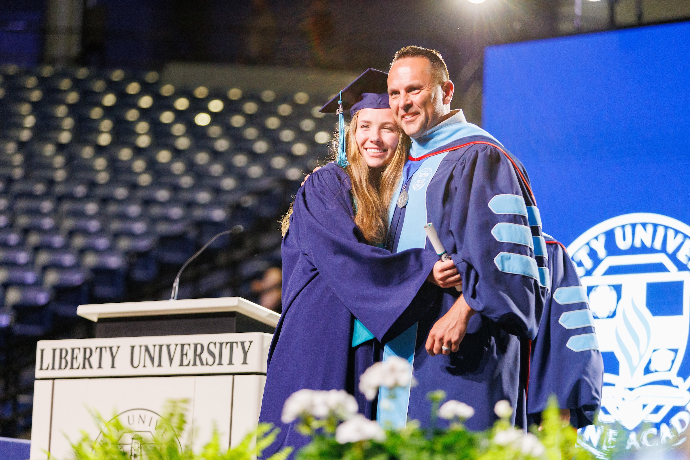 Female LUOA graduate on stage receiving her diploma from her father