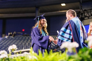 Female LUOA graduate on stage receiving her diploma