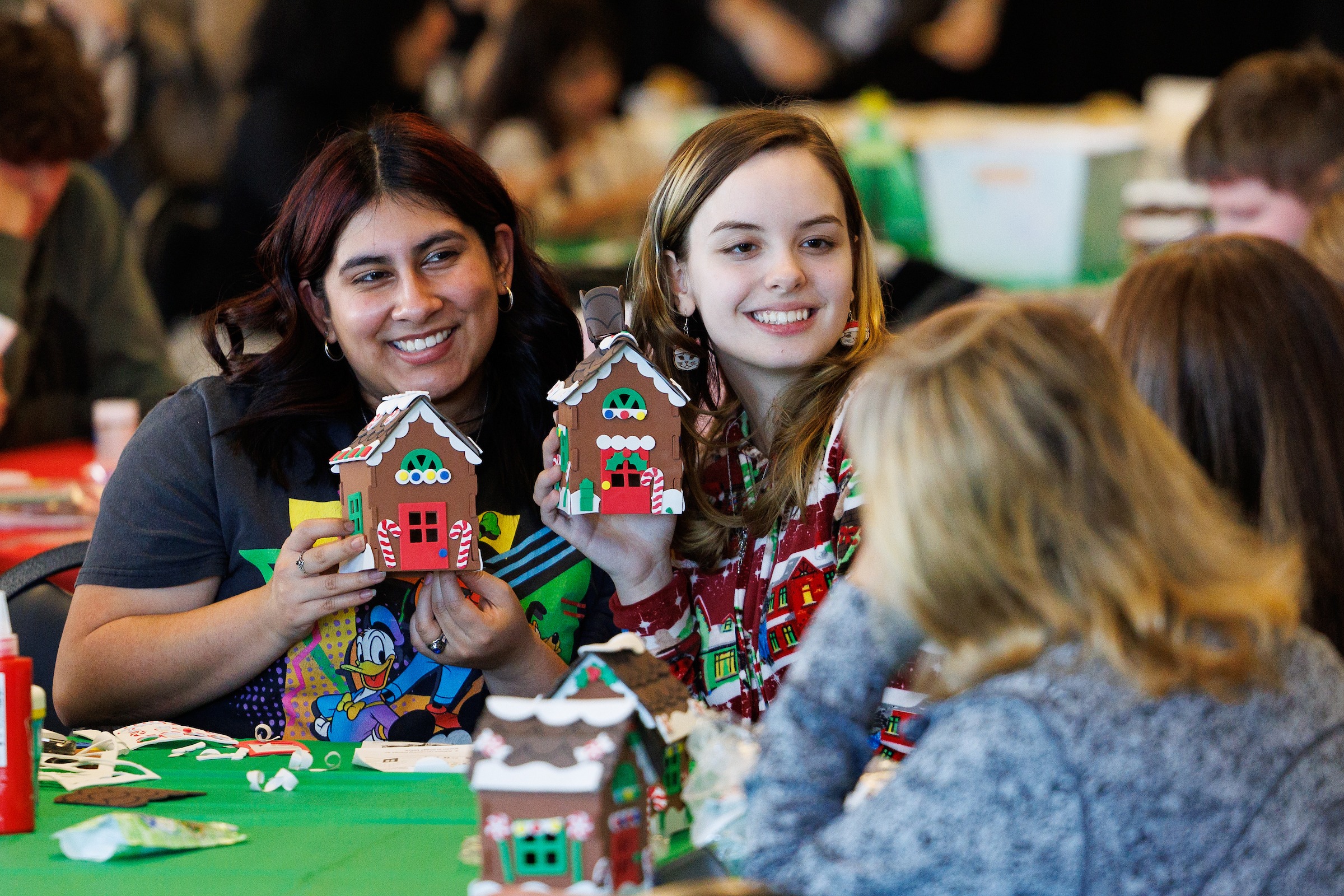 Two LUOA students building gingerbread houses at the Christmas Party