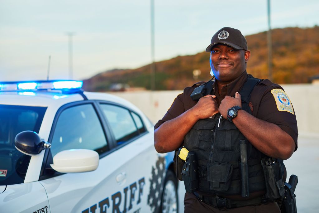 Male Police Officer Standing Next To His Police Cruiser